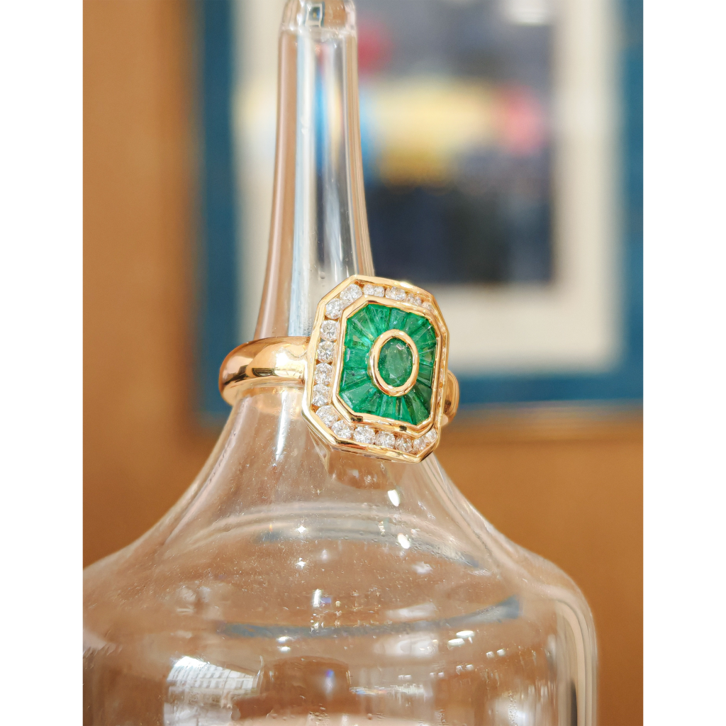 Bague vintage en or jaune sertie d’une émeraude centrale entourée de diamants, design octogonal élégant et joaillerie de luxe raffinée.