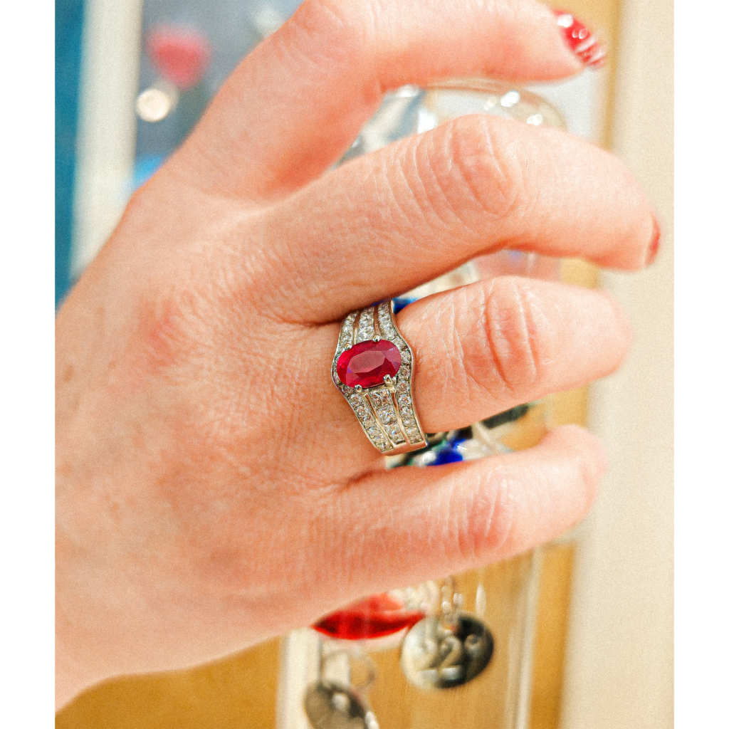 Bague en or blanc 18 carats sertie d’un rubis rouge ovale et de diamants portée à la main – bague femme luxe style joaillerie, bijoux en or 750 millièmes avec pierres précieuses, bague rubis et diamants élégante, bijouterie haut de gamme Paris, bijou raffiné femme